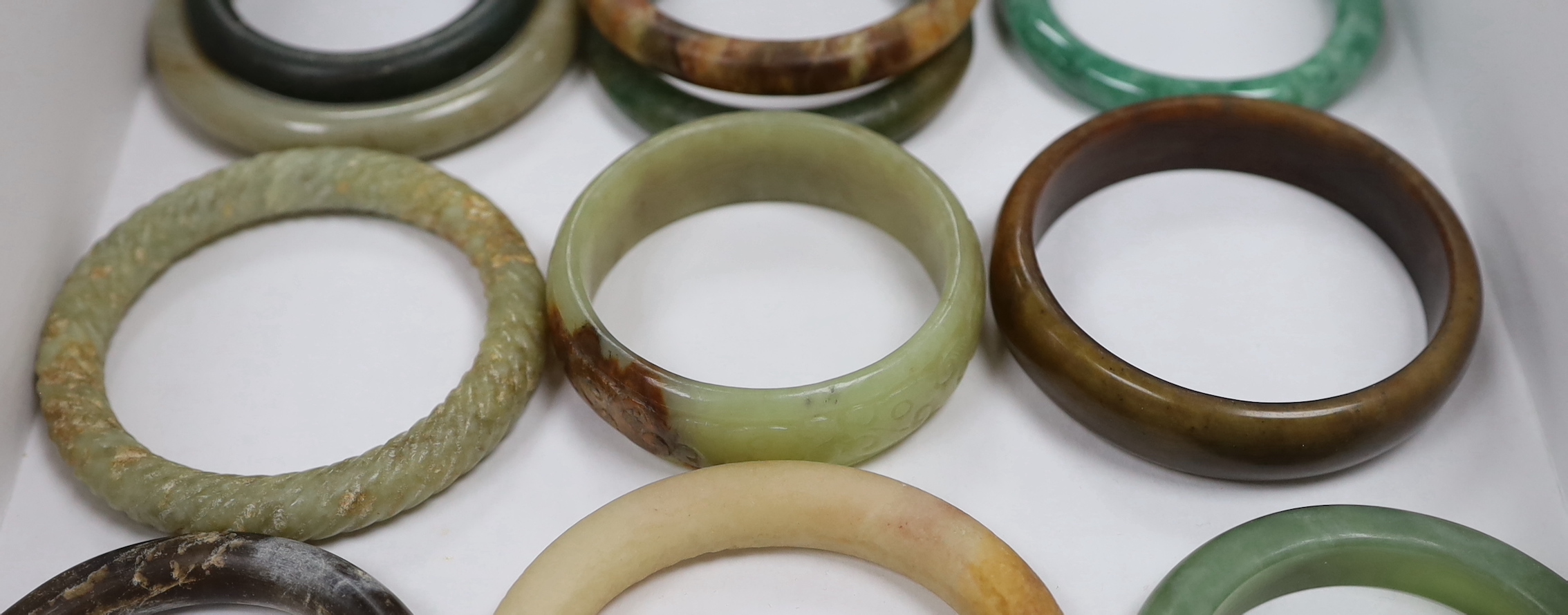 Eleven Chinese jade or hardstone bangles, largest 9cm